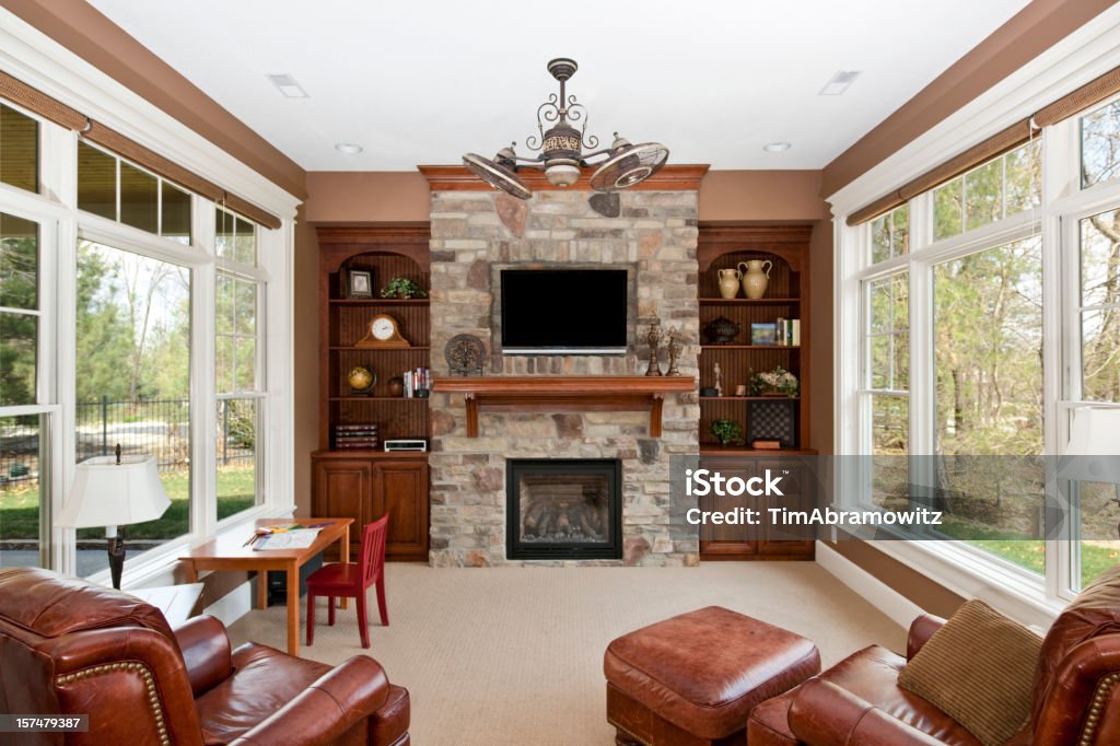 Luxury family room with stone fireplace and window walls Family room with stone fireplace and built-ins. Fireplace Stock Photo