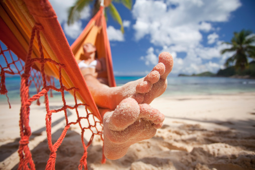 sandy toes of woman in bikini relaxing in hammock on the beach