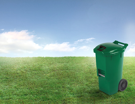Green organic garbage bin on a green lawn