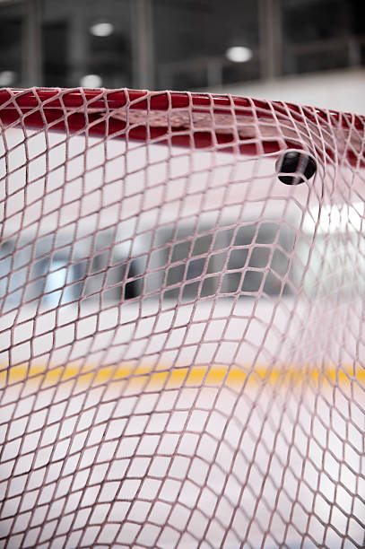 A hockey puck in motion as it enters the hockey net