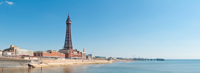 Clear blue skies over the iconic iron lattice of Blackpool Tower, pleasure beach, funfair and promenade, leisure destination for thousands of British holidaymakers for generations. ProPhoto RGB profile for maximum color fidelity and gamut.