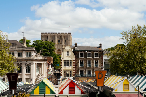 The famous market in the centre of Norwich, with Norwich Castle behind. The stone keep was constructed by order of the King between 1100 and 1120 to replace a wooden structure which stood on the same mound dating back to the Norman conquest of 1066. The castle was used as a prison until 1887 and has been used as a museum since 1894. The market is the largest Monday-to-Saturday market in the country and was founded over a millennium ago.