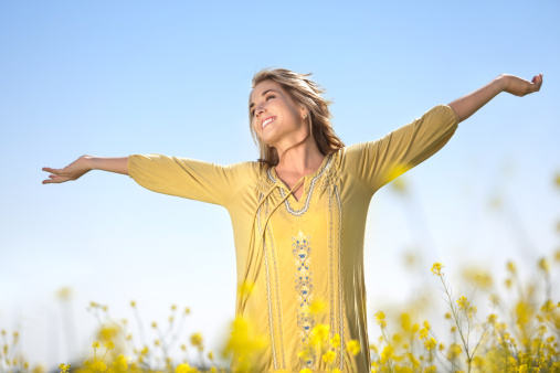 A woman lifting her arms in a field of yellow wildflowers