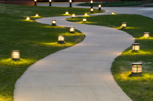 A curving sidewalk lit by small foot lights.