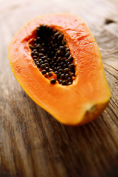 A halved fresh papaya on a wooden surface