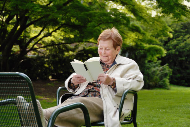 istock senior woman reading in park 157480698