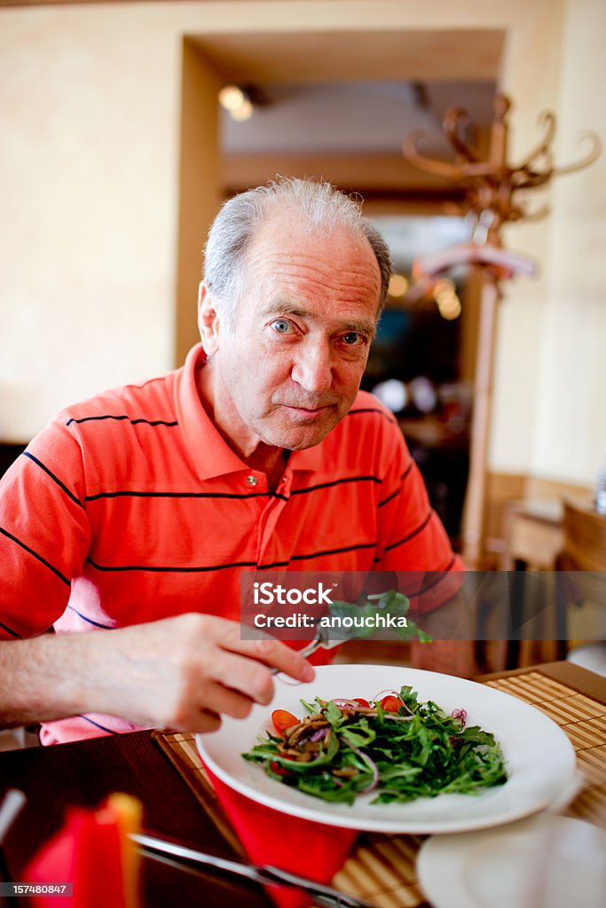 Sênior homem comendo salada ruccola - Foto de stock de Homens Idosos royalty-free