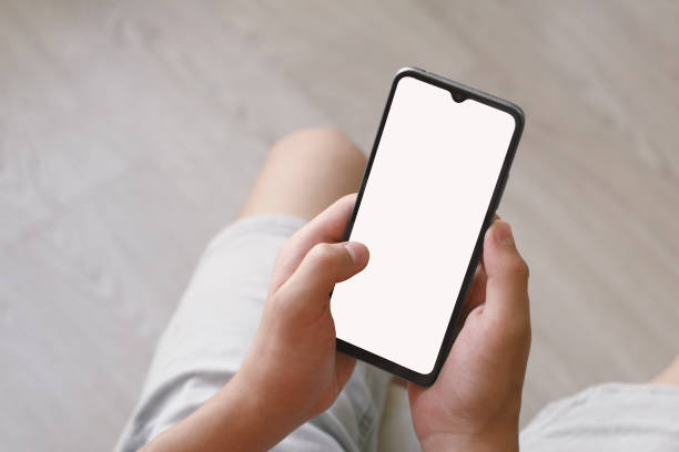 istock A teenager holds a smartphone with both hands. Phone with white screen on defocused background There is a work path in the file. 1574812953