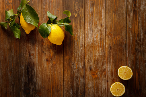 Wooden brown rustic background and lemons on a branch
