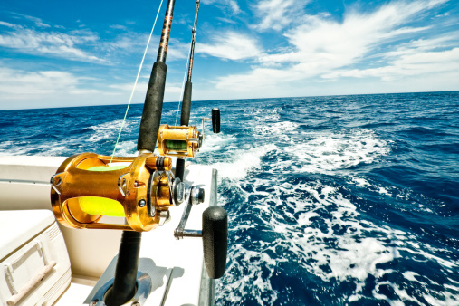 Two big fishing reels on a boat in the ocean.  These reels are used to catch big game fish such as Mahi-mahi, dorado, tuna, sailfish, swordfish sharks and marlin.  They are used in tropical and cold water oceans.
