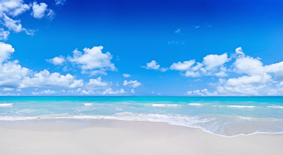 Cloudscape and gentle waves of the turquoise waters in a  Tropical island white sand beach in Venezuela. Relaxing, travel and leisure related images for vacations in the Caribbean. Image taken at Morrocoy National Park, Venezuela. Morrocoy is a coastline and a group of small islands and cays located at Falcon State in Venezuela. A very popular destination for leisure, diving, kite surfing and all kind of water activities. Morrocoy and the beauty of the turquoise coastal beaches of Venezuela are almost indistinguishable from those of the Bahamas, Fiji, Bora Bora, French Polynesia, Malau, Hawaii, Cancun, Costa Rica, Florida, Maldives, Cuba, Puerto Rico, Honduras, or other tropical areas.