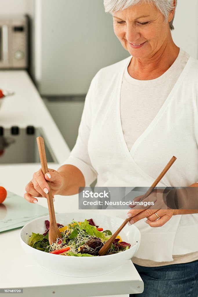 Sênior mulher preparando uma salada na cozinha - Foto de stock de 60 Anos royalty-free