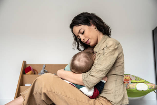 istock Young mom breastfeeding her baby on lap at home 1574820392