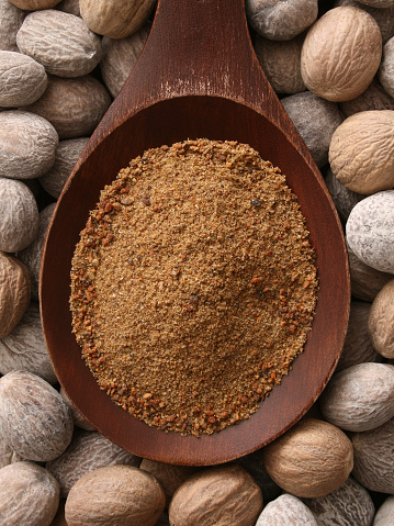 Top view of wooden spoon full of ground nutmeg