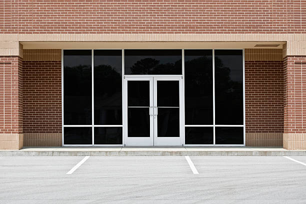 Empty Office or Storefront in Strip Mall A new unoccupied generic store front, business or professional office space in a contemporary strip mall. Red brick with dark tinted windows in brushed aluminum frames and a double door. front door photos stock pictures, royalty-free photos & images