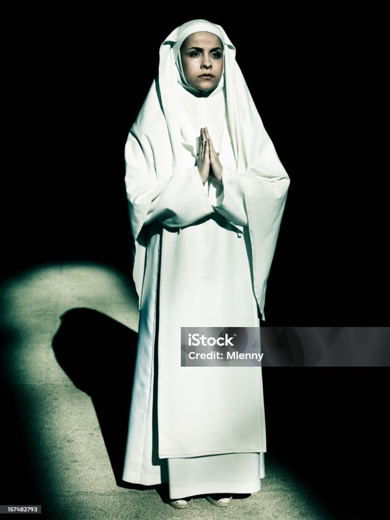 Now in Prayer Young nun praying. Light from cathedral window lighting up the scene. Hasselblad H3D-II 50 Megapixel. Edited Colors. 20-29 Years Stock Photo