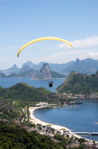 Paraglider flying with the beautiful scenary of Rio de Janeiro in the background, surrounded by Guanabara Bay on a sunny Summer day. Brazil.