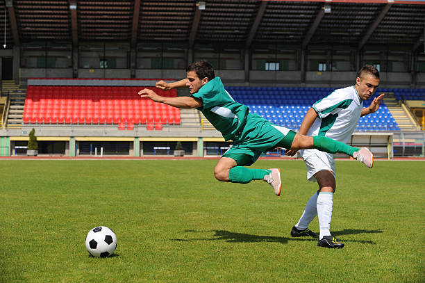 Soccer player making foul Soccer player in white dress making a foul against the one in green foul stock pictures, royalty-free photos & images