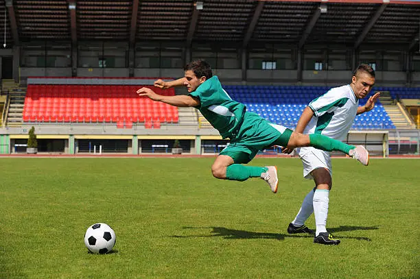 Soccer player in white dress making a foul against the one in green