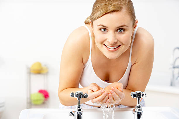 A young woman leaning over a basin and cupping water stock photo