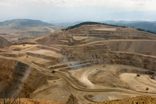 Huge ore trucks carry away tons of rock in an open pit gold mine with giant steps cut into mountain sides at the American Eagles mine in Victor Colorado.