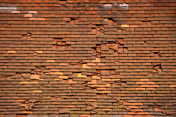 Broken tiles A tiled roof in a poor state of repair, with slipped and broken tiles. missing shingles stock pictures, royalty-free photos & images