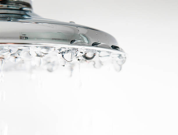 Chrome Shower Droplet Close Up Droplets of water falling from a chrome shower head.  Shallow depth of field, sharp focus on the droplets halfway across the shower head. water conservation photos stock pictures, royalty-free photos & images