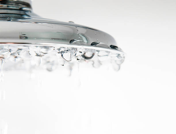 Chrome Shower Droplet Close Up Droplets of water falling from a chrome shower head. Shallow depth of field, sharp focus on the droplets halfway across the shower head. water conservation photos stock pictures, royalty-free photos & images