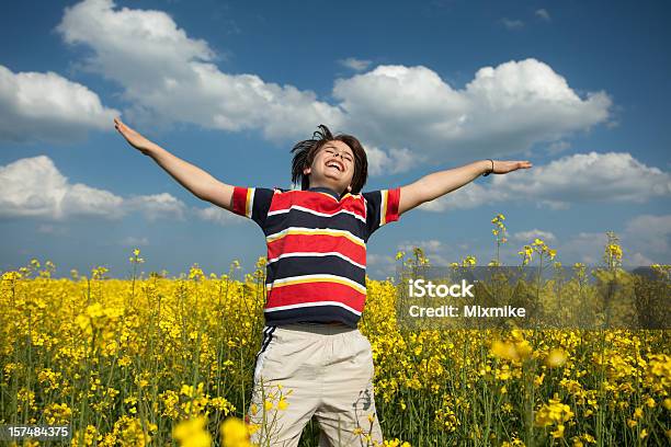 Niño Saltar En Un Jardín De Flores Amarillas Foto de stock y más banco de imágenes de Aire libre - Aire libre, Alegre, Alegría