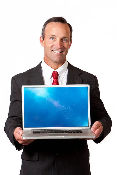 A handsome 40-45 year old caucasian businessman with a big smile presenting on a modern laptop--holding it in front of himself. isolated on a white background.