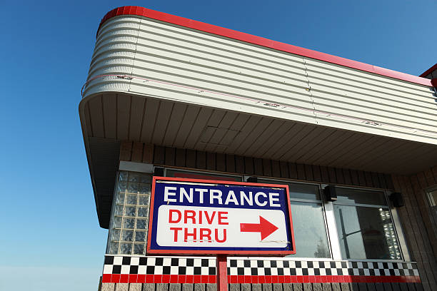 Drive thru architectuure Architectural detail of closed out drive thru establishment. Corner of the metal roof with "Entrance Drive thru" sign at the bottom. Classic 70's North American commercial architecture. fast food restaurant stock pictures, royalty-free photos & images