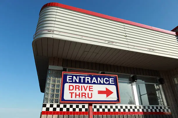 Architectural detail of closed out drive thru establishment. Corner of the metal roof with "Entrance Drive thru" sign at the bottom. Classic 70's North American commercial architecture.