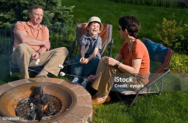 Famiglia Rilassante Intorno Fuoco - Fotografie stock e altre immagini di Focolare all'aperto - Focolare all'aperto, Famiglia, Giardino domestico