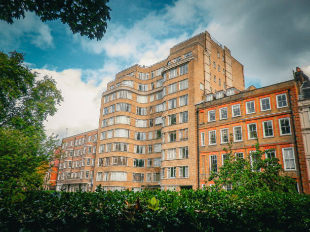 Stock photo shows a modern apartment blocks with red brick built flats in a London suburb, exemplifying council-style housing. This suburban residential scene highlights urban architecture, community living, and affordable housing solutions