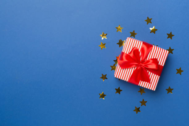 istock Gift box and stars confetti on color background, top view 1574914420