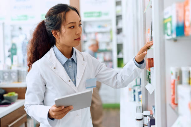 istock Young Chinese pharmacist going through medicine inventory while working in a pharmacy. 1574921250