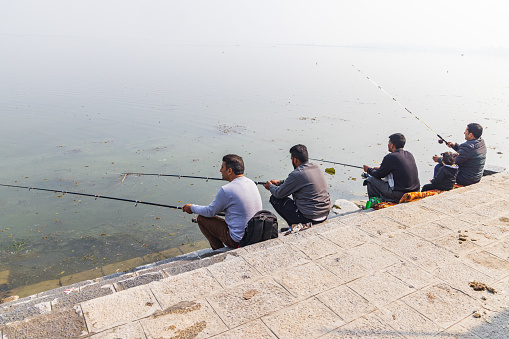 Hazratbal, Srinagar, Jammu and Kashmir, India. October 30, 2022. Men fishing on the shore of Dal Lake.