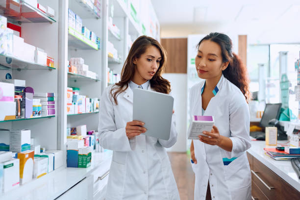 istock Young female pharmacist cooperating while working on touchpad in a pharmacy, 1574921776