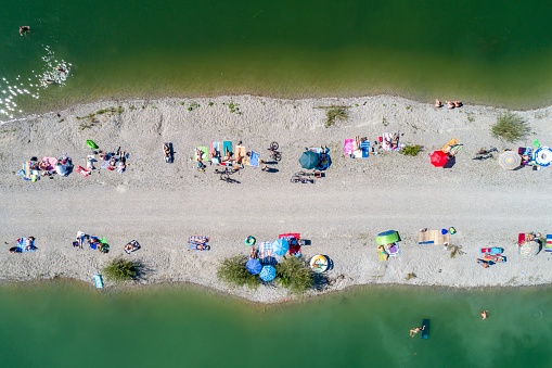 People sunbathing on the beach and swiming in the lake viewed from directly above.