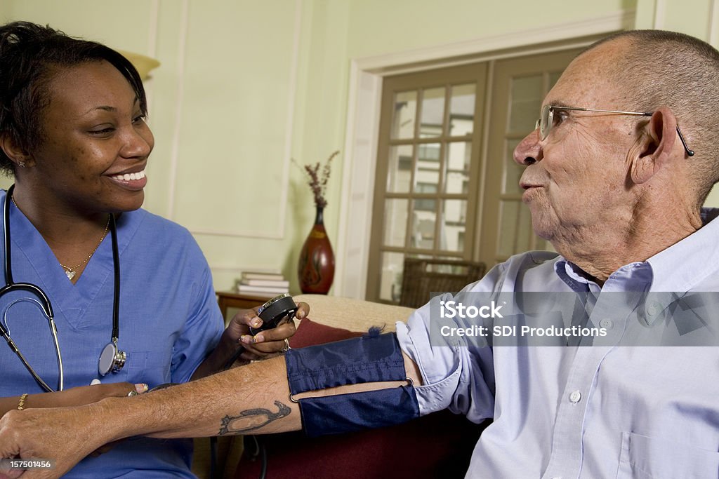 Pielęgniarki w podeszłym wieku opieki zdrowotnej sprawdzania jej pacjenta ciśnienia krwi - Zbiór zdjęć royalty-free (Afrykanin)