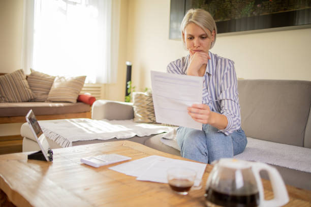 istock Young woman using calculator while going through bills and home finances 1575016782