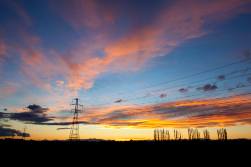 Spectacular sunset on the Canterbury Plains on New Zealand's South Island. Power lines & pylons stretch into the distance.