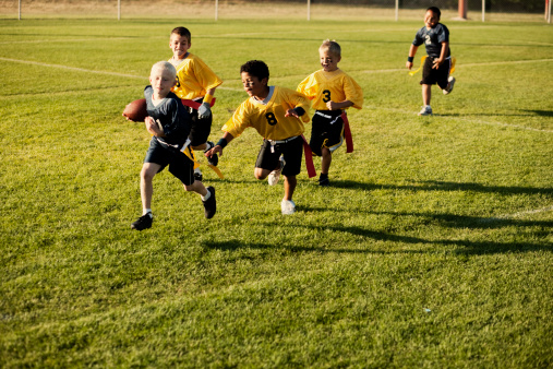 A young boy goes for the flag football touchdown.