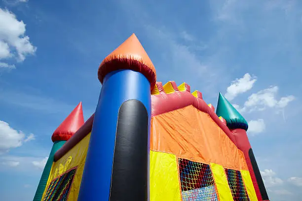 Stock photo of the top half of a children's inflatable bouncy castle with a blue sky and clouds.