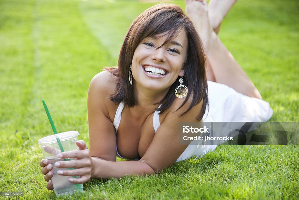 매력적인 젊은 여자 라잉 on 잔디 차가운 음료 - 로열티 프리 가슴 골 스톡 사진
