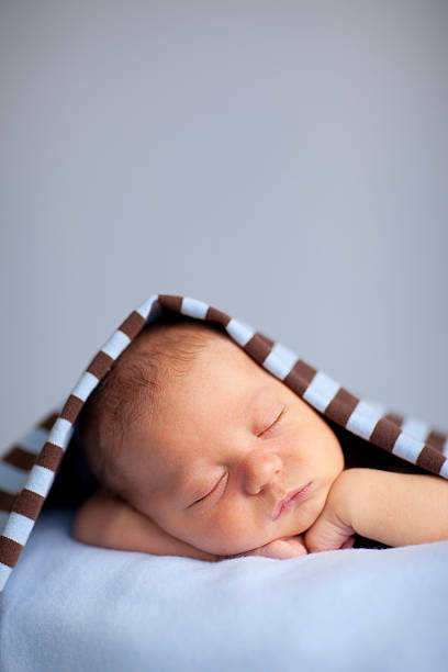 istock Newborn Baby Boy Sleeping Peacefully Under Striped Blanket 157502524