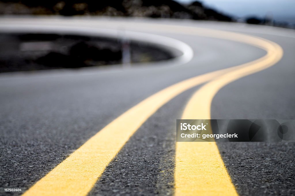 Yellow Lines on a Winding Road A double yellow line on a road curving into the distance. Road Stock Photo