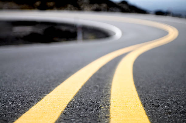 Yellow Lines on a Winding Road A double yellow line on a road curving into the distance. symmetry photos stock pictures, royalty-free photos & images