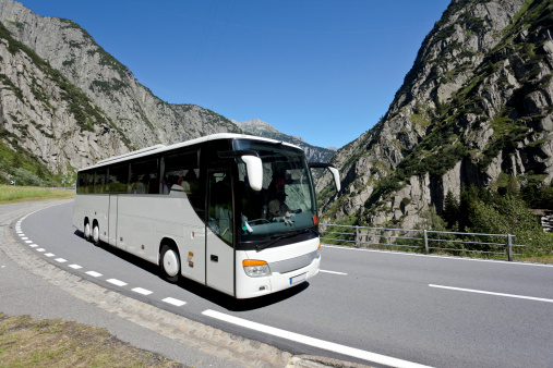 White tourist bus going around tight hairpin turn in a mountain road