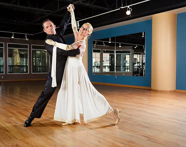 A couple ballroom dancing in an empty dance studio.